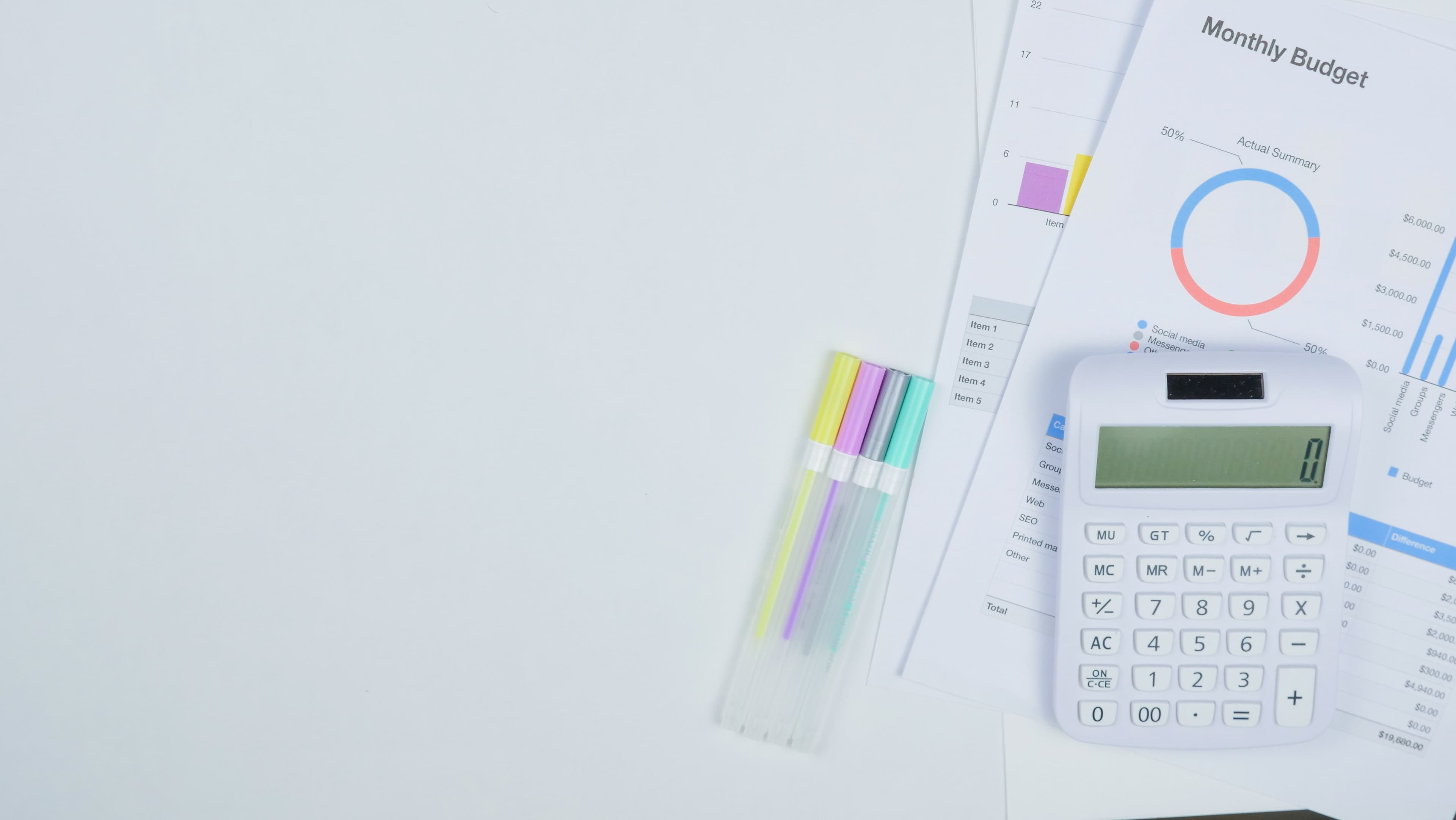 Budget planning workspace with calculator, financial charts, graphs, colorful markers, and monthly budget spreadsheet showing data analysis and financial planning